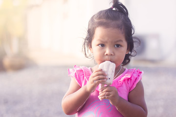 Cute little girl is eating icecream,soft color filter