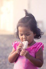 Cute little girl is eating icecream,soft color filter