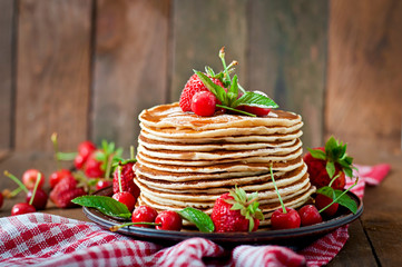 Pancakes with berries and syrup in a rustic style