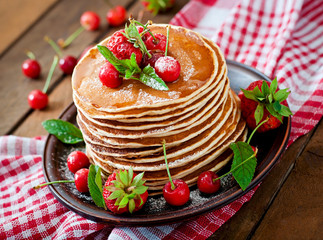 Pancakes with berries and syrup in a rustic style
