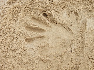 Male hand print in the salt sand on the beach.