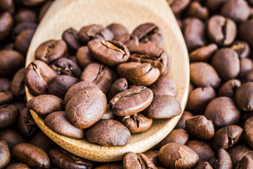 close up of coffee beans on wooden spoon