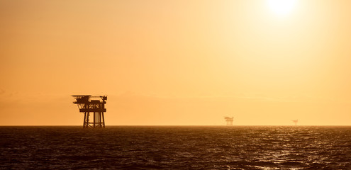 Silhouette of oil platform at sunset