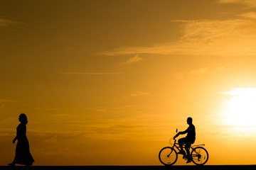 Obraz na płótnie Canvas Silhouette man riding the bike at sunset