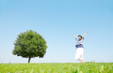原っぱで深呼吸する女性