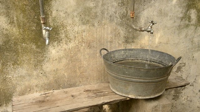 Water pouring out of a tap into an antique galvanized basin