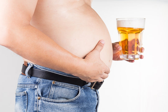 Obese man with big belly holding a glass of cold beer