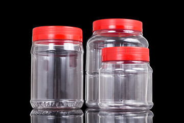 Three translucent plastic PVC jar with red cover isolated in black