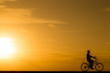 Naklejka na ściany i meble Silhouette man riding the bike at sunset