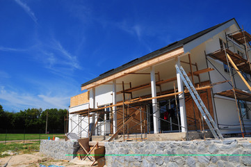 New frame house under construction against blue sky