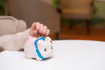 貯金箱に硬貨を入れる女性の手