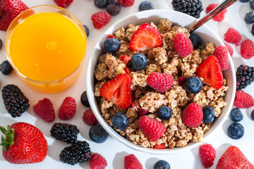 Top view of muesli with red fruits and orange juice.