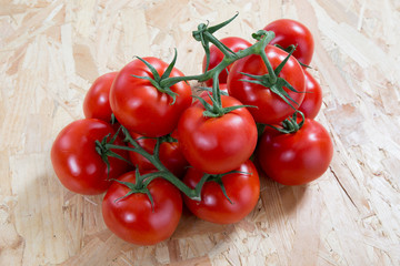 Fresh  tomatoes on a cluster over wooden  table