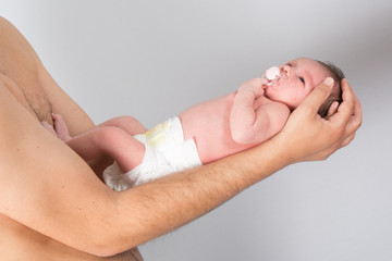 New born baby is held in father arms on grey backgroud