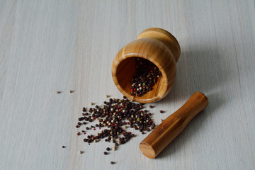 Black, white, red, green peppercorns in w wooden mortar