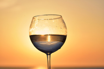 glass with wine at sunset on the table above the sea ocean