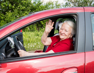 Smiling old woman sitting in the car