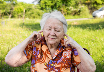 Old woman  covers her ears with  hands