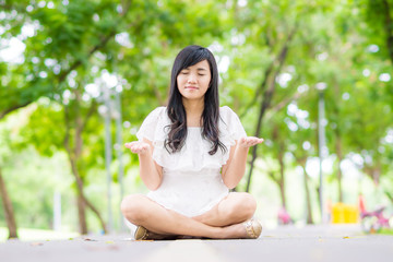 Pretty asian woman doing yoga exercises in the park