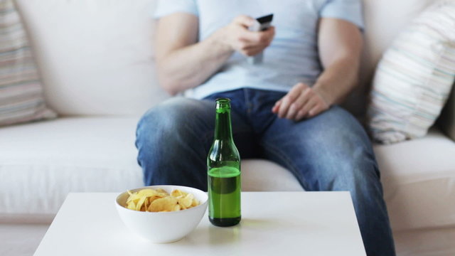 close up of man with beer and remote at home