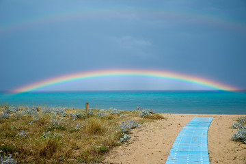 Regenbogen über türkis blauem Meer mit Steg