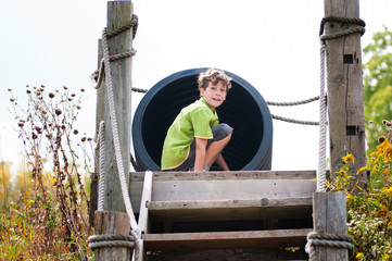 child about to go down a big tube slide at a rural playground