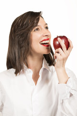 Beautiful young woman eating an red apple, studio shot on white