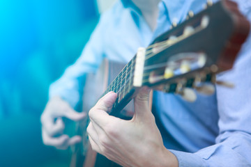 Young musician playing at acoustic guitar