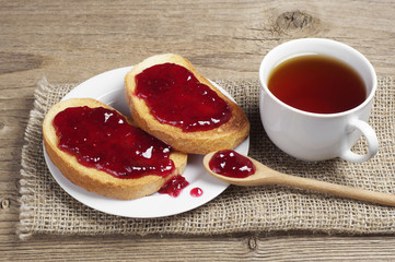 Cup of tea and white bread with strawberry jam