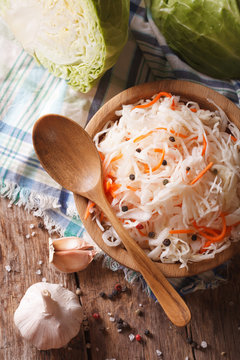 sauerkraut and carrots in a wooden plate close up vertical top view
