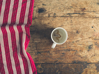 Empty cup and tea towel on wooden table