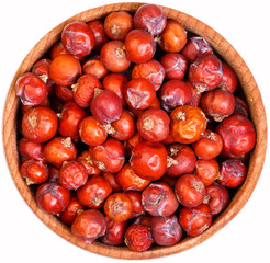 Dry Juniper seed in a small wooden bow isolated on white.