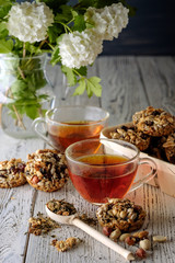 Cup of tea and cookies made of nuts and raisins.