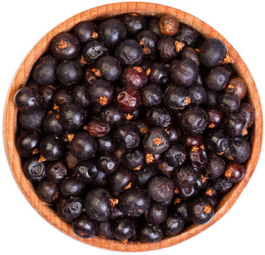 Dried Juniper berries in a small wooden bow isolated on white.