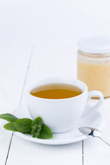 Mint tea with honey on wooden table.