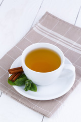 Mint tea with cinnamon on wooden table.