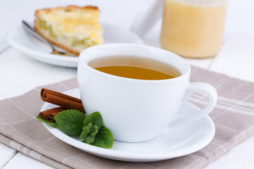 Mint tea with cinnamon on wooden table.
