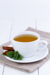 Mint tea with cinnamon on wooden table.