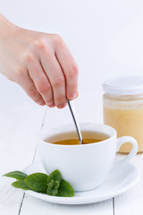 Mint tea with honey on wooden table.