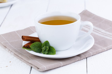 Mint tea with cinnamon on wooden table.