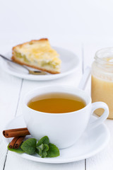 Mint tea with cinnamon on wooden table.