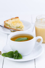 Mint tea with slice of rhubarb pie on wooden table.