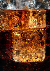 Bubbles in the glass of cola with ice.