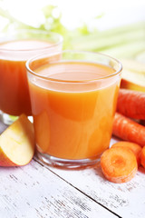 Glasses of juice with apple and carrot on wooden table close up