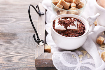 Hot chocolate with marshmallows in mug, on tray, on color wooden background