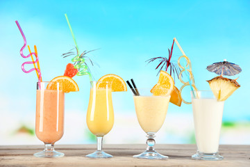 Summer cocktails on wooden table on bright blurred background