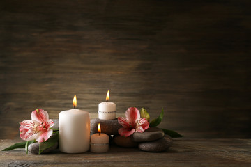 Obraz na płótnie Canvas Beautiful composition with candles and spa stones on wooden background