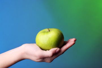 Female hand with apple on colorful background