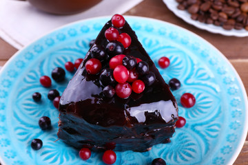 Delicious chocolate cake with berries on plate on table close up