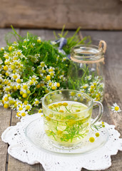 Chamomile tea in a glass cup on a wooden background